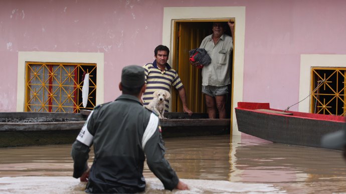 Residents and a police officers walk through a flooded street of Honda, Colombia