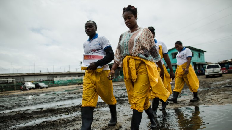 Community Health Volunteers with Ebola prevention kits walking through West Point in Monrovia, Liberia