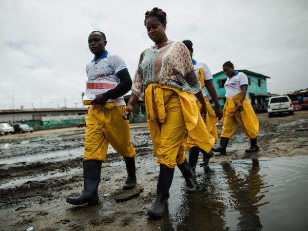 Community Health Volunteers with Ebola prevention kits walking through West Point in Monrovia, Liberia